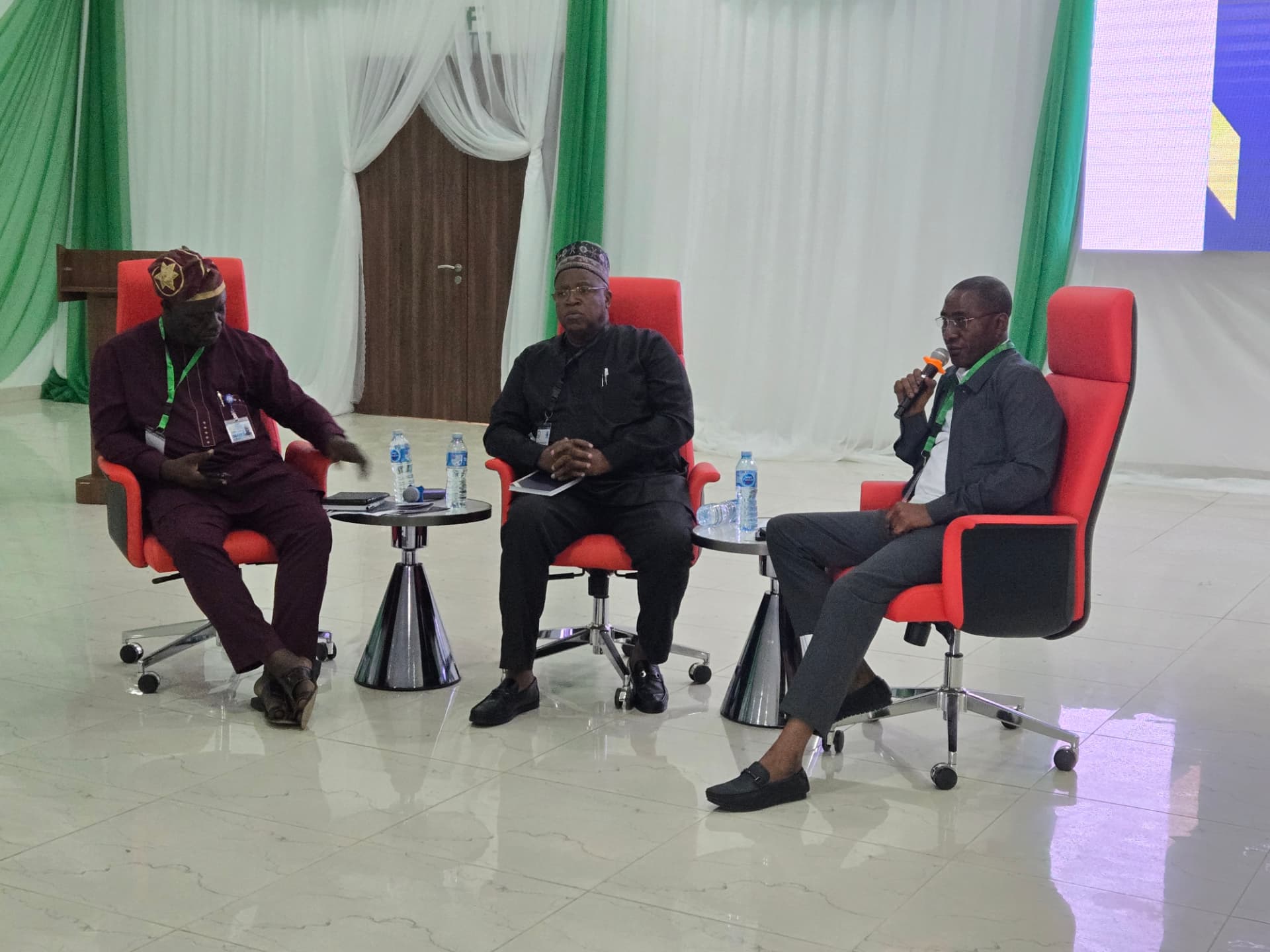 Three speakers taking part in a conference panel discussion